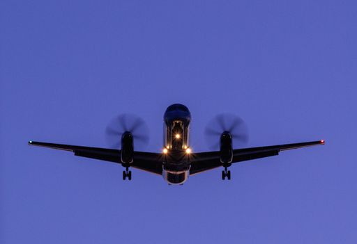 A plane preparing to land at the airport against a blue sky at night
