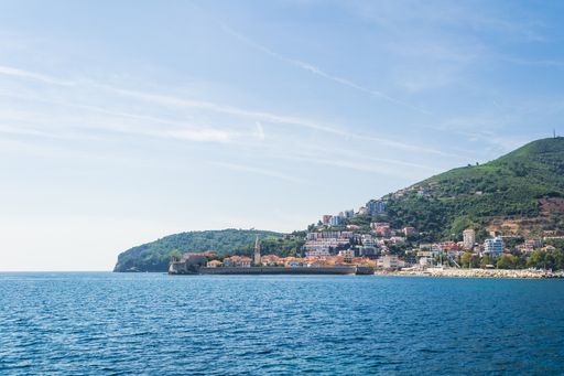 A high angle shot of an ocean and a town on the shore with a mountain in the background