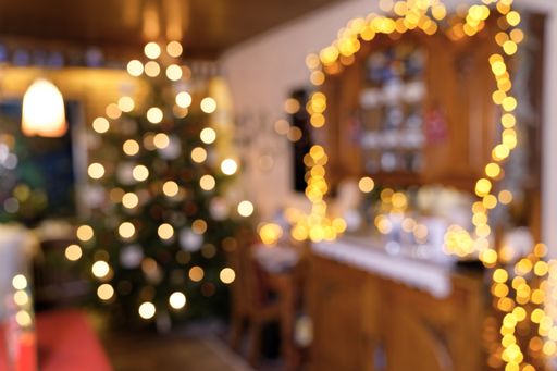 blurred atmospheric closeup image of a room section during Christmas time, lighted by the Christmas Tree, some LED fairy lights, a ceiling lamp and so