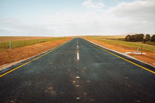 A single lane newly built rural road through fields