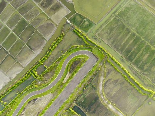 A top view shot of a highway near lakes and agricultural fields