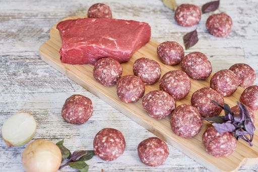 A closeup shot of fresh raw meatballs on a wooden board