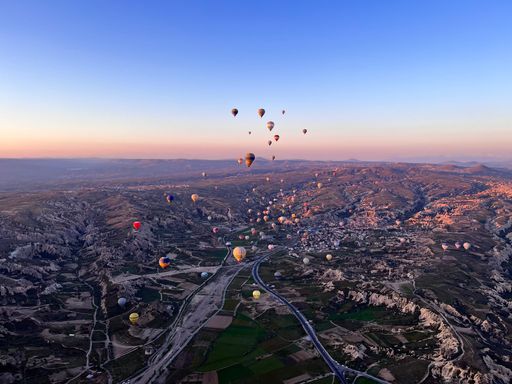 Colorful hot air balloons float above a town and road