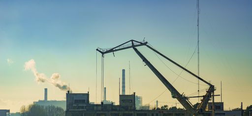 A view of an industrial site with a crane on sunset sky background
