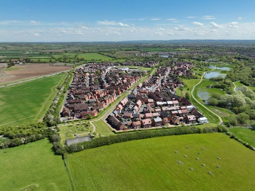 Drone photography of an English housing estate in Aylesbury. Buckingham Park in May 2024. Aerial view of a housing estate surrounded by green fields