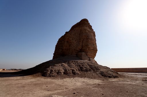 The Ziggurat of Akarkuf and a large boulder under a clear blue sky in Baghdad.