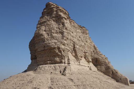 The Ziggurat of Akarkuf and a large boulder under a clear blue sky in Baghdad.