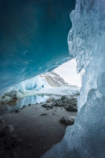 Winter landscape view from the interior of an ice cave in Zinal glacier with a frozen cascade in the foreground