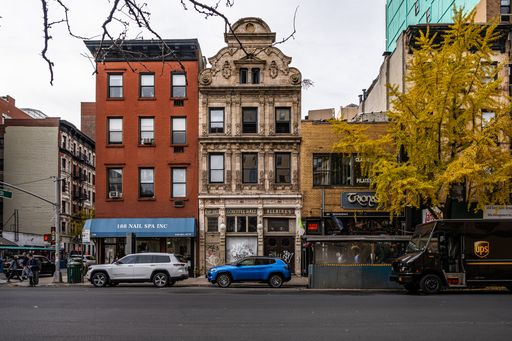 A blue and a white car parked by an urban building in New York