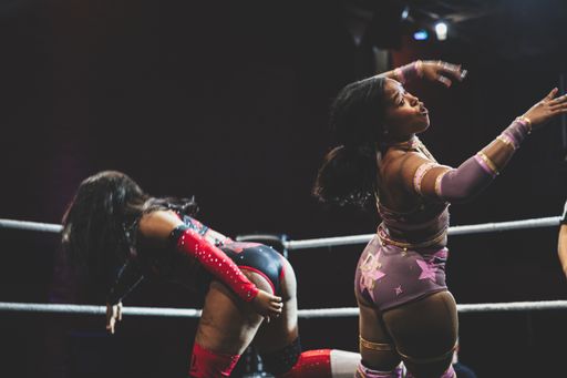 A woman competes in a wrestling match with bent legs, standing