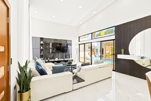 A contemporary living and dining area with expansive windows overlooking the pool