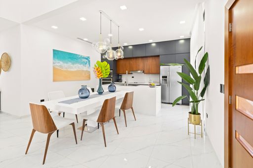 A spacious kitchen with white tiled floors and dining space