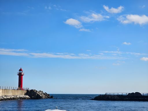A red lighthouse on the pier against the blue sky and sea. Gangwon-do, South Korea