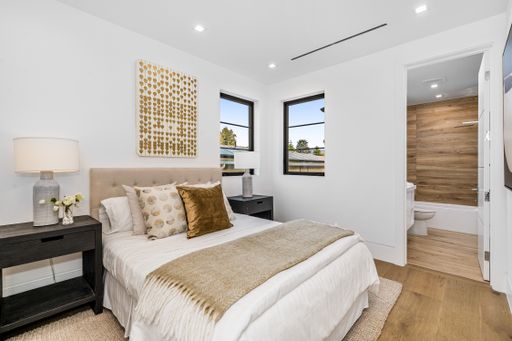 A large bed, white walls, and hardwood floors in a bedroom