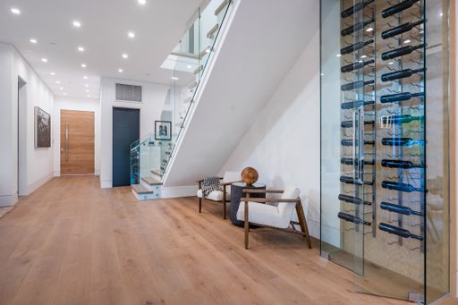 An empty chair in a room with white walls, wooden floors, and a staircase