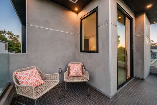 Wicker chairs on a balcony with large windows