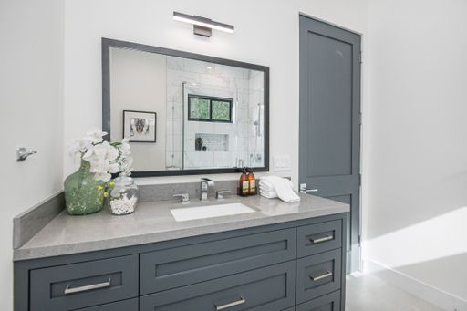 A gray bathroom sink and shower stall in a modern new construction home in Los Angeles