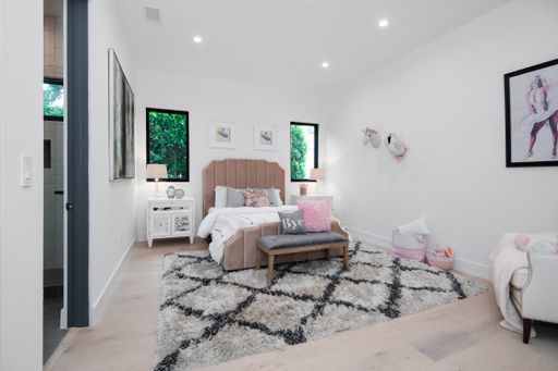 A minimalist all-white bedroom with furniture in a modern new construction home in Los Angeles