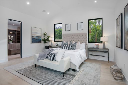 A minimalist white bedroom with a gray rug in a modern new construction home in Los Angeles