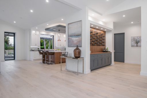 A white kitchen with island and multiple chairs in a modern new construction home in Los Angeles