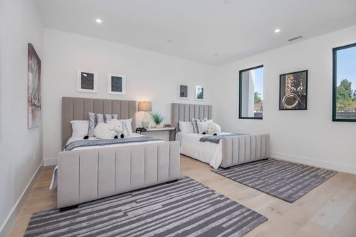The two neatly made beds in a white bedroom in a modern new construction home in Los Angeles