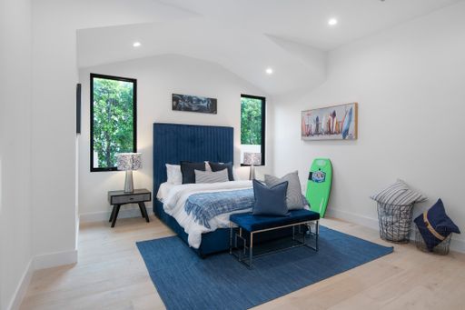 A bedroom with a blue rug and bed in a modern new construction home in Los Angeles