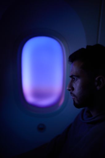 A man seated by an airplane window at night