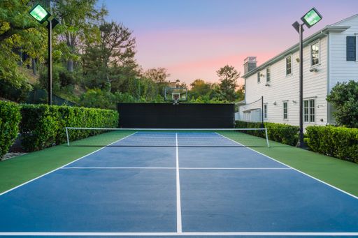A tennis court outdoors surrounded by trees by a new construction home in Encino, California