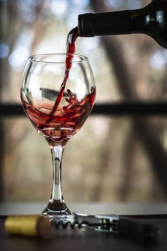A closeup shot of red wine pouring in glass isolated on blurry background