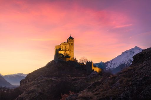 A beautiful view of the Valere Basilica in Sion at sunset with pink and orange colors