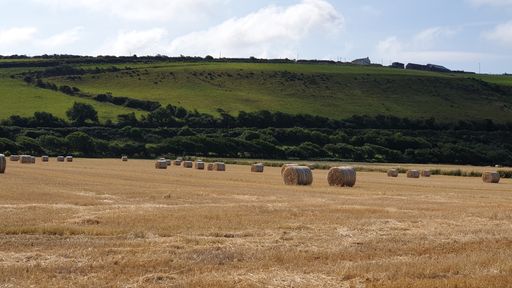 A high angle shot of a field with hills on the background under a blue sky