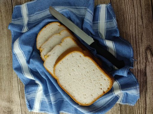 A top view of a knife and cut bread pieces on the kitchen towel