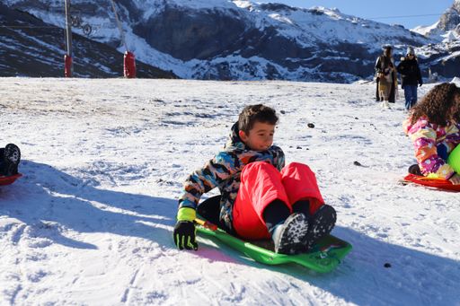 A boy smiling, enjoying and having fun sledding on the snow in Andorra, Spain