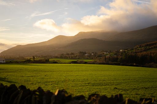 A grassy field with a wooden fence in the foreground in Mourne mountains in Northern Ireland