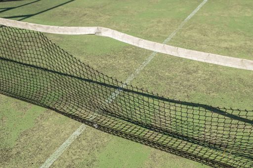A closeup of the netting of an abandoned and weathered paddle tennis court