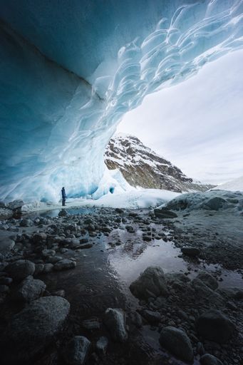 A vertical shot of the Zinal ice cave with a hiker looking at the ice above