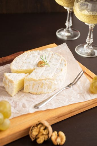 A plate with cheese, nuts, grapes, and wine glasses