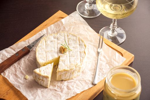 A cheese and white wine on a wooden cutting board