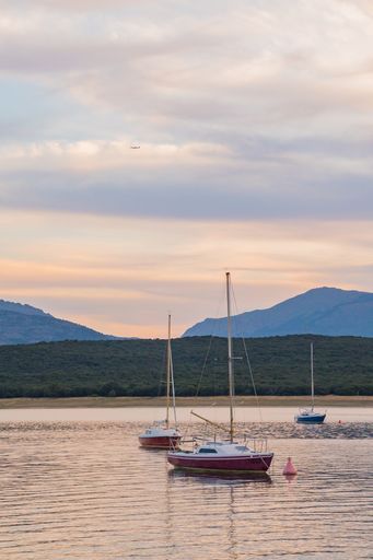 A closeup of docked sailboats on the river with a sunset background