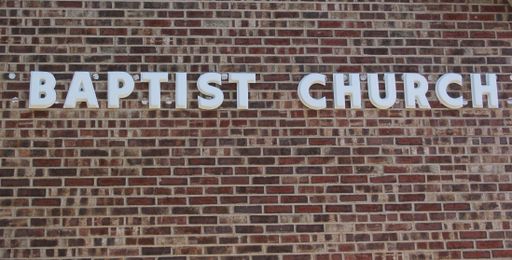 A brick wall with a baptist church sign