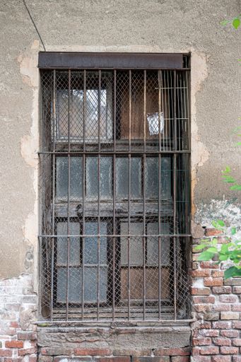 A vertical shot of a window with old rusty fences on a building in the daylight