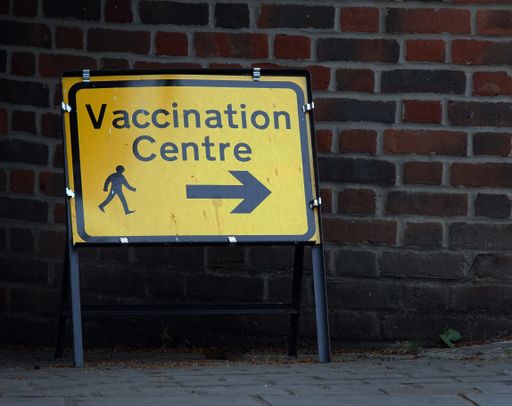 A closeup shot of a yellow billboard sign showing the direction of the vaccination center