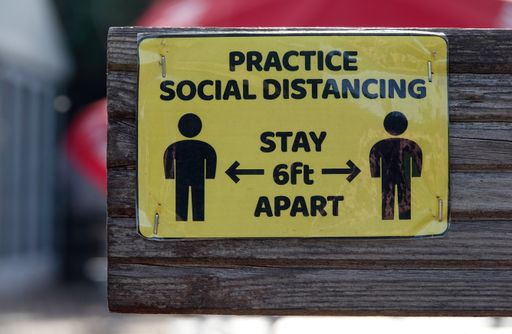 A closeup shot of a yellow sign giving instructions on how to social distance