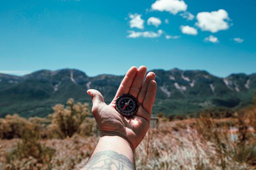 A shot of the man's hand holding a compass to orient himself on the mountain.
