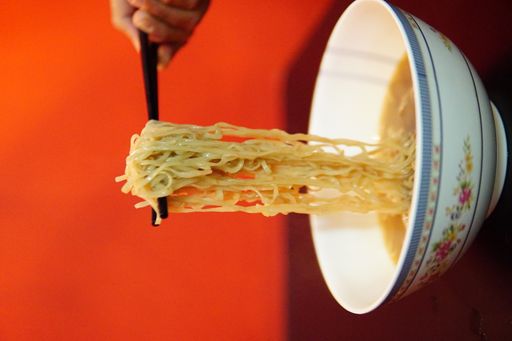 A closeup of noodles on the chopsticks; ramen - traditional Japanese soup