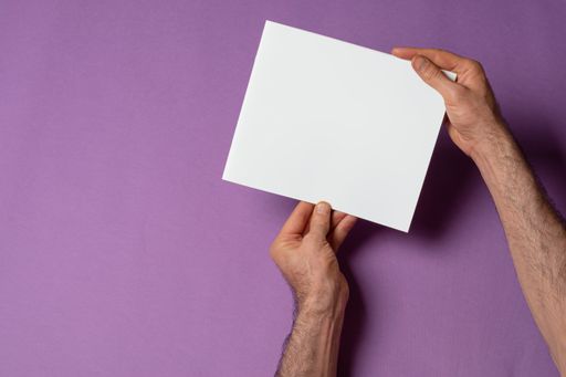 A male hands holding a catalog with blank cover on purple background - editable mockup template