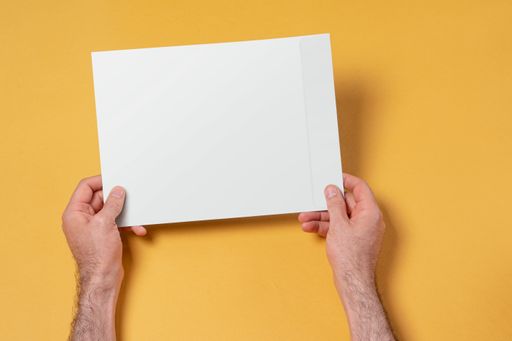 A Male hands holding an A4 paper envelope against yellow background - editable mockup template
