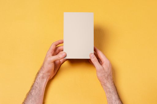 A male hands holding a small blank box on a yellow background - editable mockup template