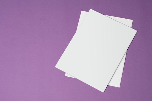 A top view of two tri-fold catalogs with blank covers on a purple surface - editable mockup template