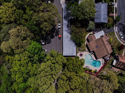 An aerial top view of houses, cars, and trees in a residential area